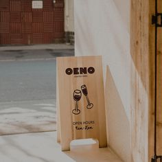 a wooden sign that says open hours and two wine glasses on the side of a building