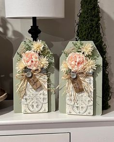two vases with flowers are sitting on a shelf next to a lamp and potted plant