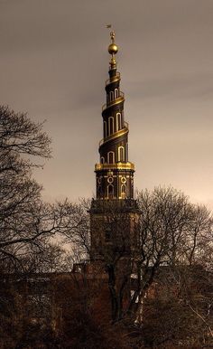 a very tall tower with a clock on it's side in the middle of trees