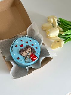 a cake in the shape of a kissing couple on top of a box next to tulips