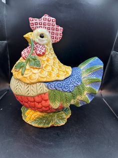 a ceramic chicken sitting on top of a black surface