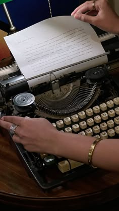 a person typing on an old fashioned typewriter with a green lamp in the background