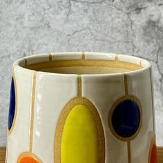 a close up of a cup on a table with a marble wall in the background
