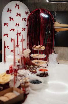 a table topped with lots of food next to a red curtain