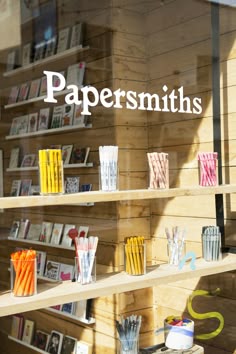 a store front window with papers and pencils on display in the window, along with bookshelves