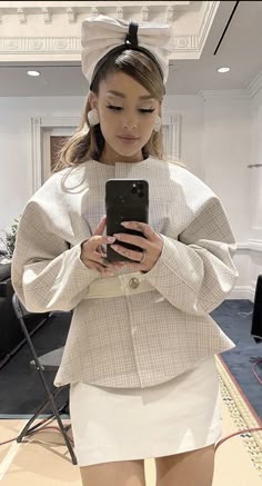 a woman standing in front of a mirror looking at her cell phone