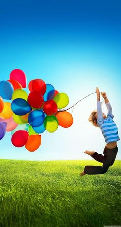 a person jumping in the air while holding onto some colorful balloons with their hands and feet