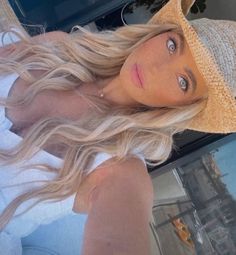 a woman with long blonde hair wearing a hat