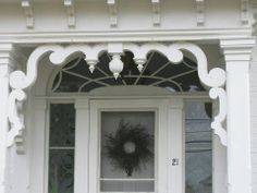 a white front door with a wreath on the window sill and two lights above it