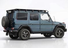 a blue mercedes benz g - class is parked on a white surface with no one around it