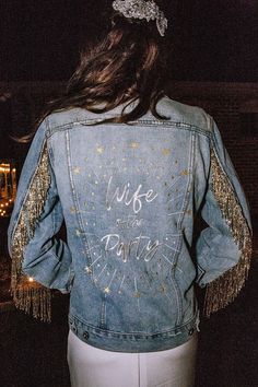 the back of a woman wearing a denim jacket with gold sequins on it