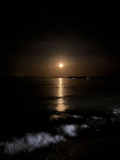 the moon is shining over the ocean at night