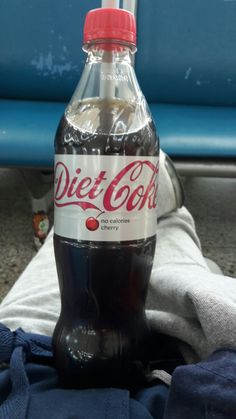 a bottle of diet coke sitting on top of a blue chair next to a towel