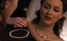 a woman looking at herself in the mirror with jewelry on her neck and necklace around her neck