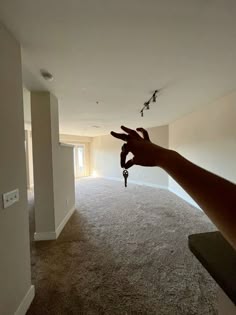 a person's hand reaching up towards the ceiling in an empty room with no carpet