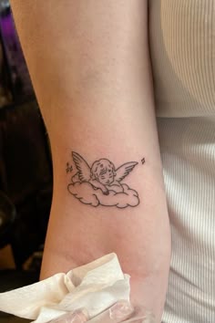 a woman with a small tattoo on her arm and the angel is flying in the sky