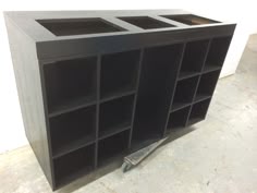 a black bookcase sitting on top of a floor next to a white wall and some tools