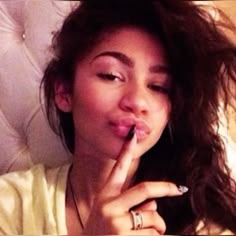 a woman laying on top of a bed with her finger in her mouth