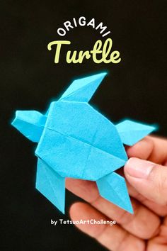 the origami turtle is made from blue paper and sits in someone's hand