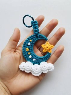 a hand holding a crocheted keychain with a star and moon on it