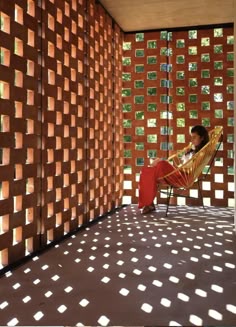 a woman sitting on a chair in front of a wall made of squares and dots