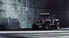 a black jeep parked in front of a concrete wall with lights on it's hood