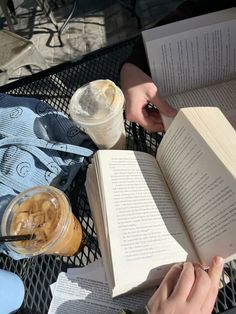 an open book sitting on top of a table next to a cup of coffee and a drink