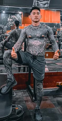 a man with tattoos on his chest and leg standing in front of a gym bench