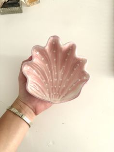a hand holding a pink shell shaped bowl