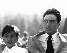 a man in a suit and tie standing next to a young boy wearing a vest