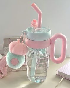 a pink and blue cup sitting on top of a desk next to a laptop computer