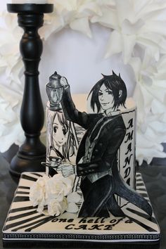 a black and white cake sitting on top of a table next to a vase with flowers