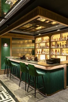 a bar with green chairs and bottles on the shelves