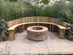 an outdoor fire pit surrounded by plants and flowers