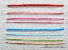 several different colored threads on a white surface