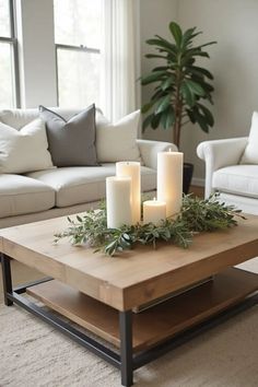 a living room with white couches and candles on top of a coffee table in front of a window