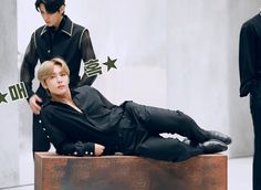 a man laying on the ground next to two mannequins wearing black clothing