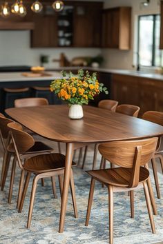 a wooden table with chairs around it and a vase filled with yellow flowers on top