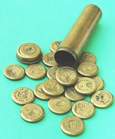 a pile of gold coins sitting on top of a blue table next to a metal tube