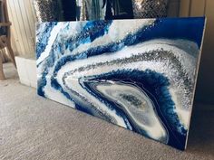 a large blue and white painting sitting on top of a carpeted floor
