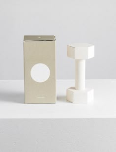 a white object sitting on top of a table next to a cardboard box with a hole in it