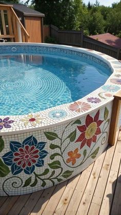 an above ground swimming pool with flowers on the side and wooden decking around it