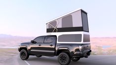 a truck with a camper attached to the back driving down a road near mountains