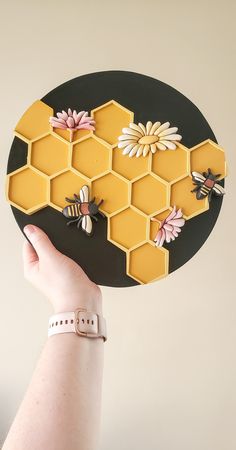 a person holding up a piece of paper with bees and honeycombs on it