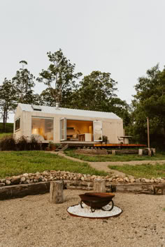 a small house sitting on top of a lush green field next to a fire pit