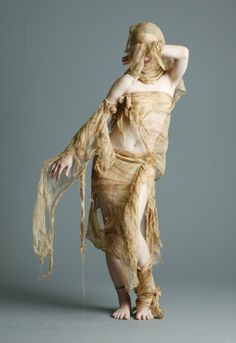 a woman in a dress with her hands on her head and arms behind her back