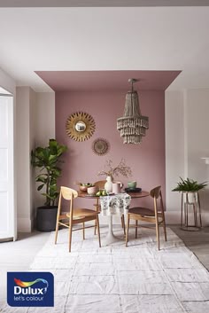 a dining room with pink walls and chandelier hanging from the ceiling over a table