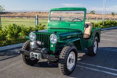 an old green jeep parked in a parking lot