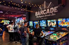 people are playing pinball games at the barcade, which is open for business