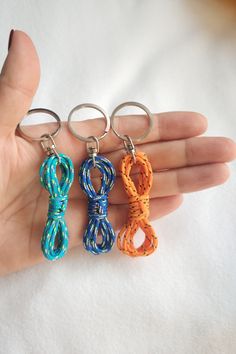 three different colored key chains in the palm of someone's hand, with one knot on each end